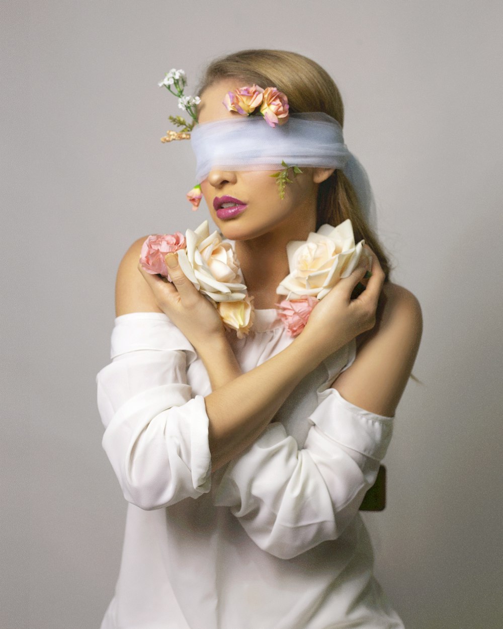 donna in camicia bianca a maniche lunghe con fiore bianco sull'orecchio