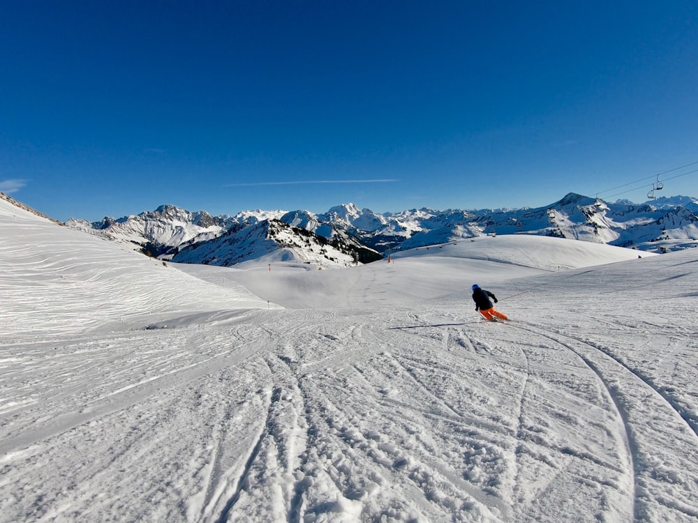 personne en veste rouge équitation sur une planche de ski rouge et noire sur une montagne enneigée pendant