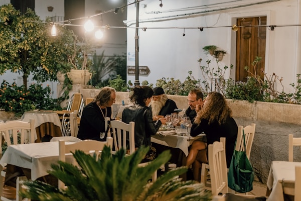Friends enjoying a meal together in a cozy, movie-like setting in the town of Vieste, Puglia, Italyby Gabriella Clare Marino