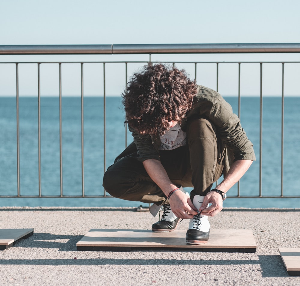 woman in green t-shirt and black pants sitting on concrete floor