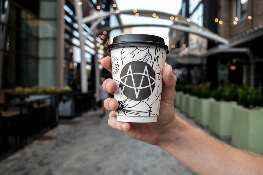 person holding white and black disposable cup