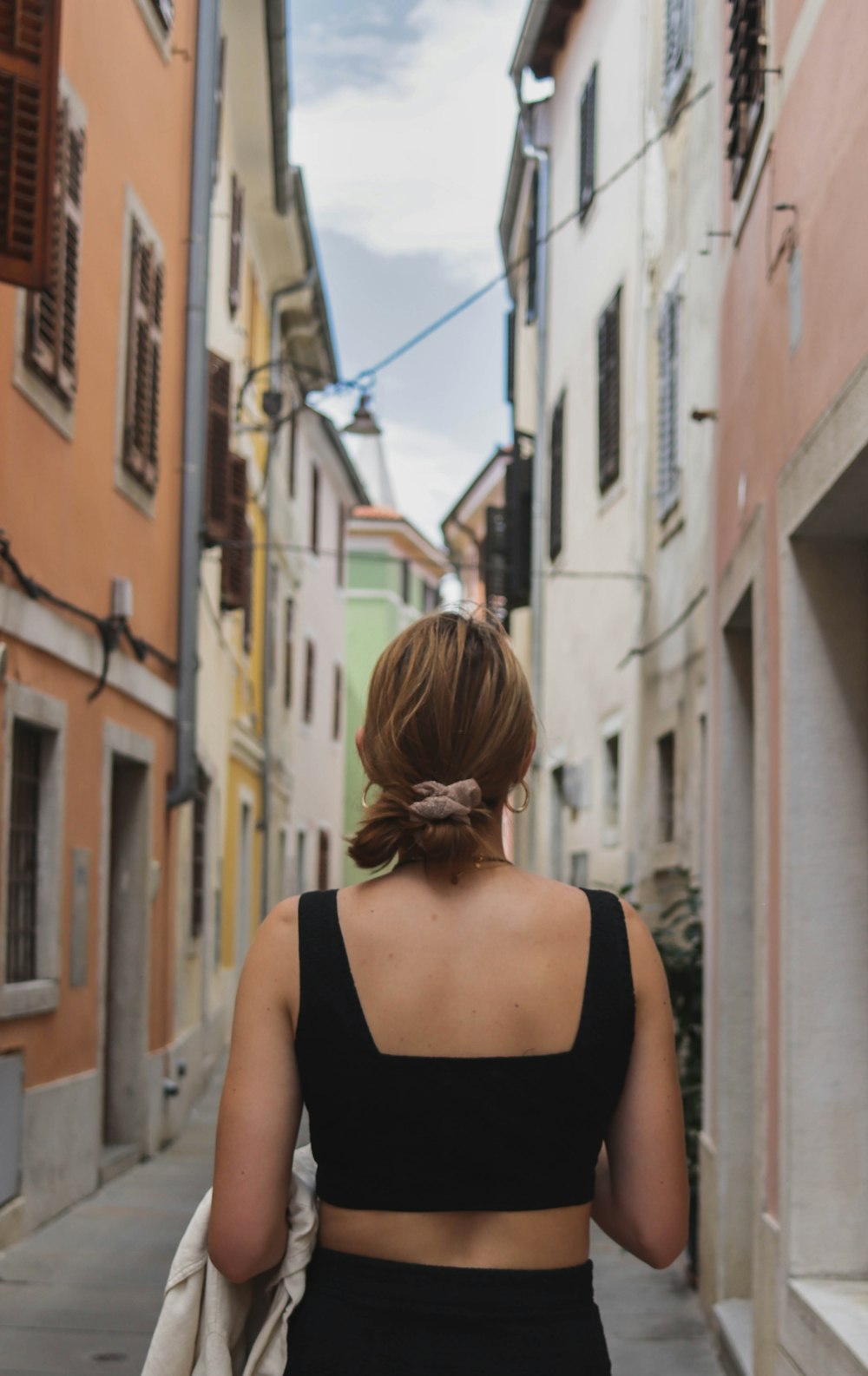 woman in black tank top standing in front of brown concrete building during daytime