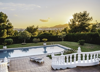 white outdoor pool near green trees during sunset