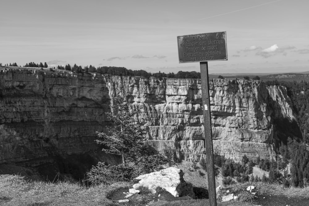 Una foto en blanco y negro de un letrero al borde de un acantilado