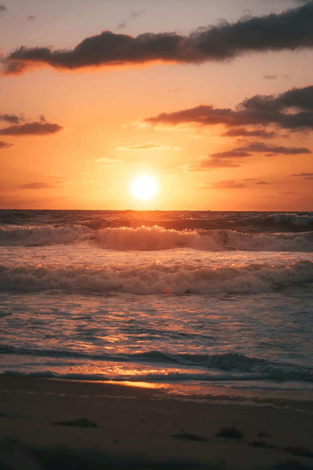 sea waves crashing on shore during sunset