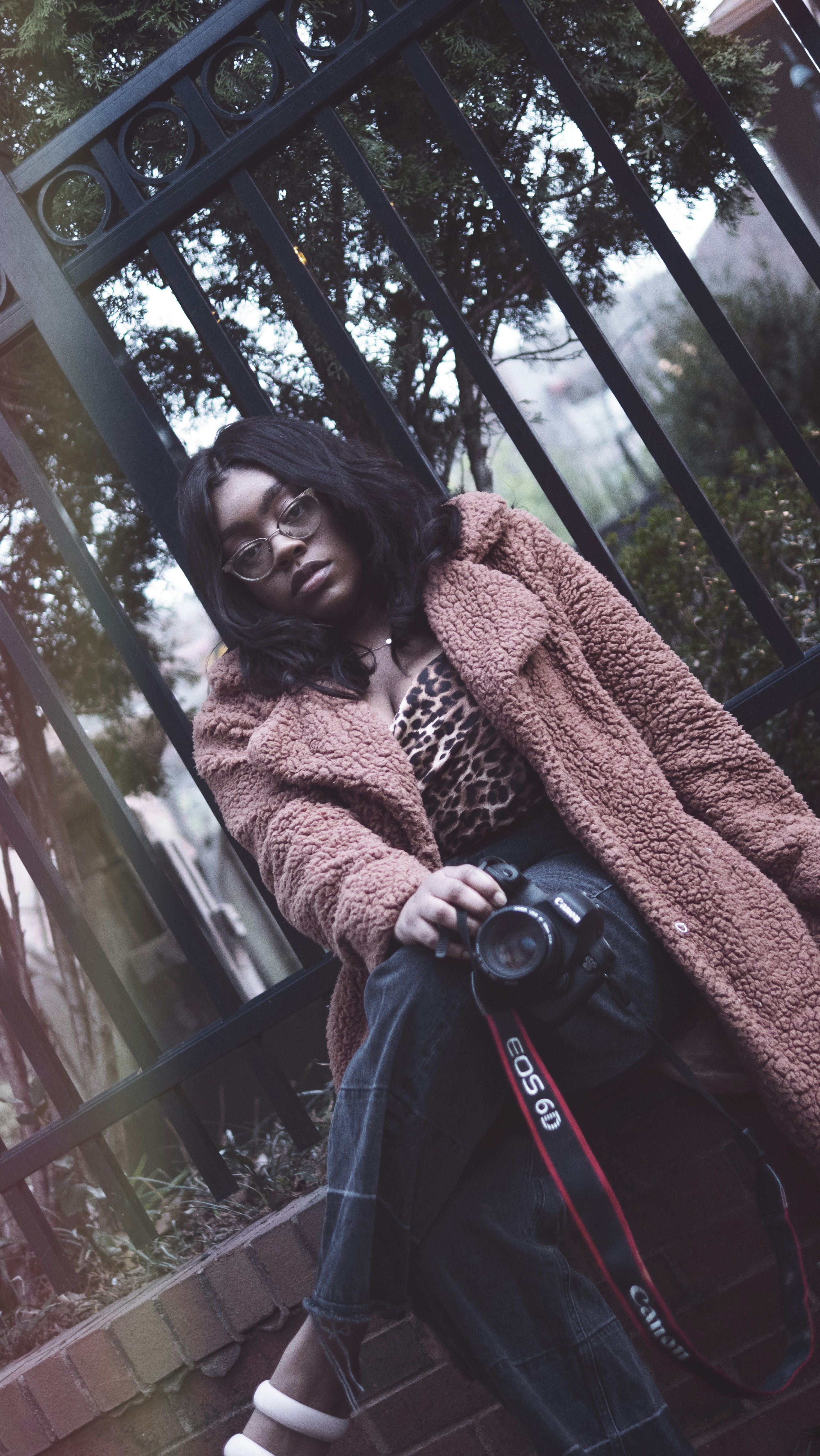 茶色のスカーフとブルーデニムのジーンズを着た女性が黒い椅子に座っています