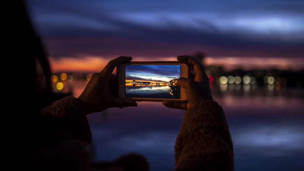 person holding clear glass mug with beer during sunset