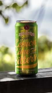 Close-up of a lime green Mulli Mix can with dewy condensation beside a golf ball on the tee.