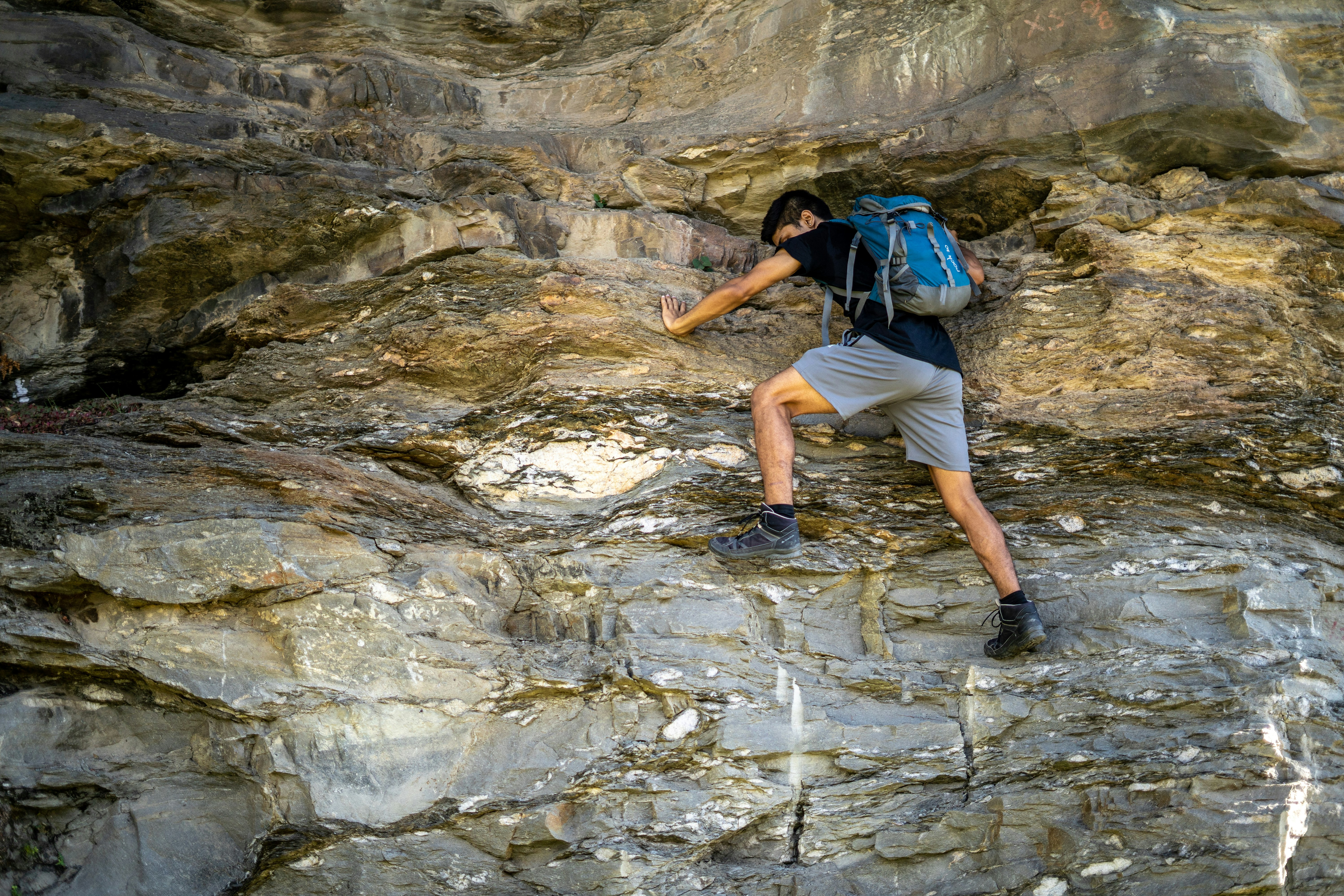 man in blue t-shirt climbing on rocky mountain during daytime