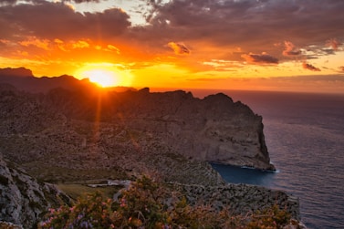 gray rocky mountain beside body of water during sunset