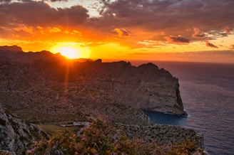 gray rocky mountain beside body of water during sunset
