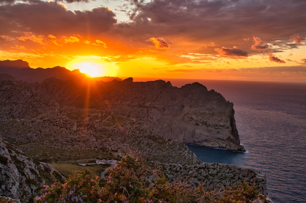 Montaña rocosa gris al lado del cuerpo de agua durante la puesta del sol