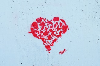 A graffiti-style red heart composed of various animal silhouettes and abstract shapes stands out against a textured light blue background.