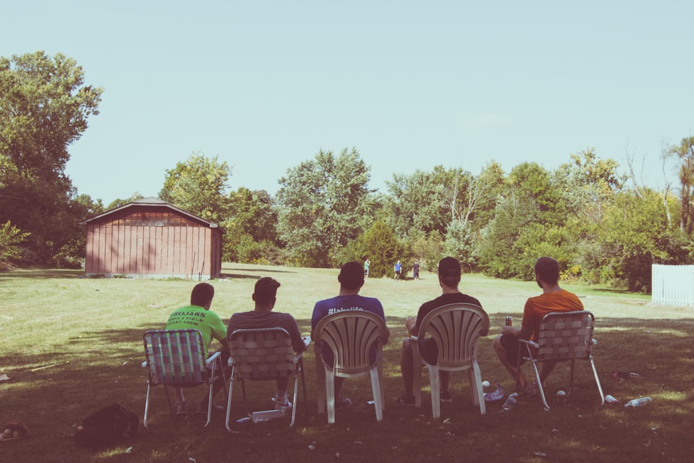 people sitting on white plastic chairs during daytime