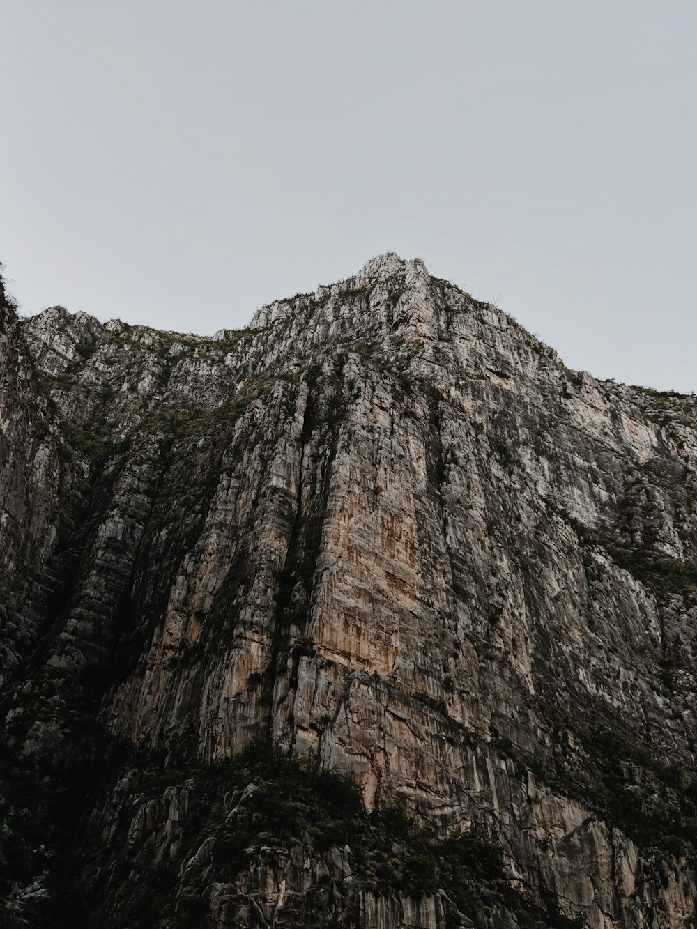 montagna rocciosa marrone e grigia sotto il cielo bianco durante il giorno