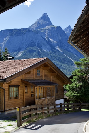 A cozy wooden chalet surrounded by lush green trees under a bright blue sky.