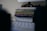 A stack of colorful notebooks rests on top of a white electronic device with a perforated front panel featuring a 'G' logo. The scene is dimly lit, creating an intimate and cozy atmosphere in an indoor setting.