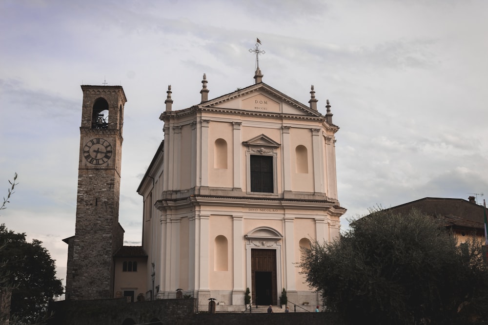 chiesa in cemento bianco vicino agli alberi verdi sotto le nuvole bianche durante il giorno