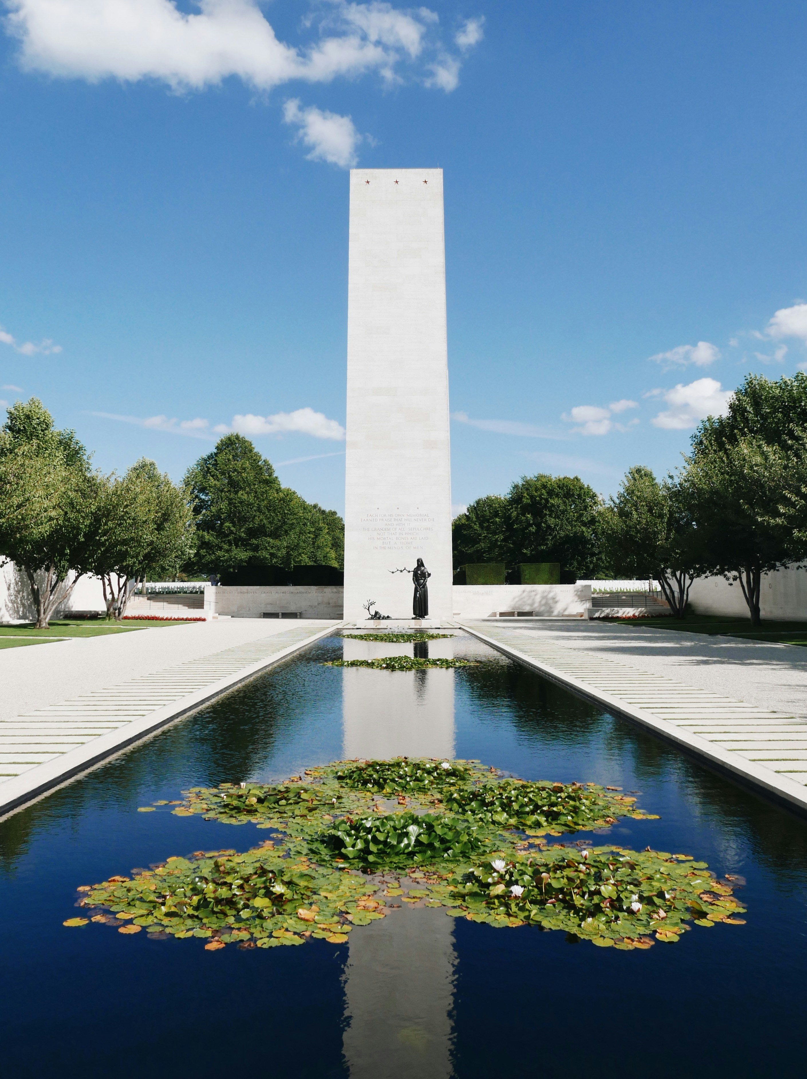 gray concrete monument near green trees under blue sky during daytime