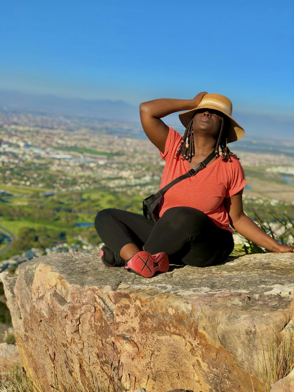 woman in black tank top and black pants sitting on brown rock during daytime