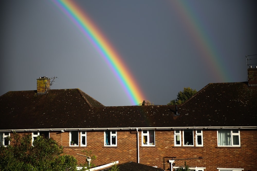 brown and white concrete house under rainbow