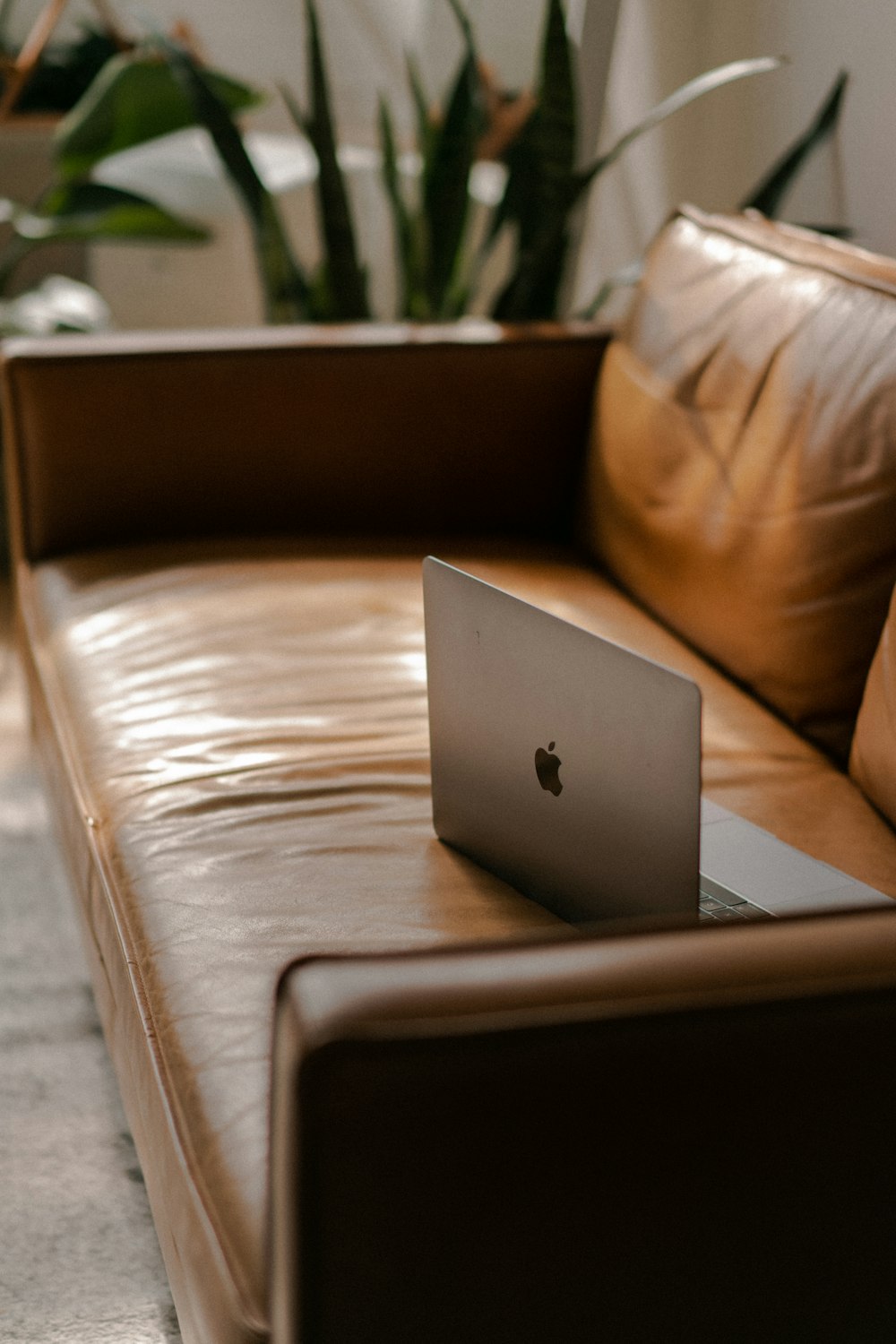 silver macbook on brown leather couch