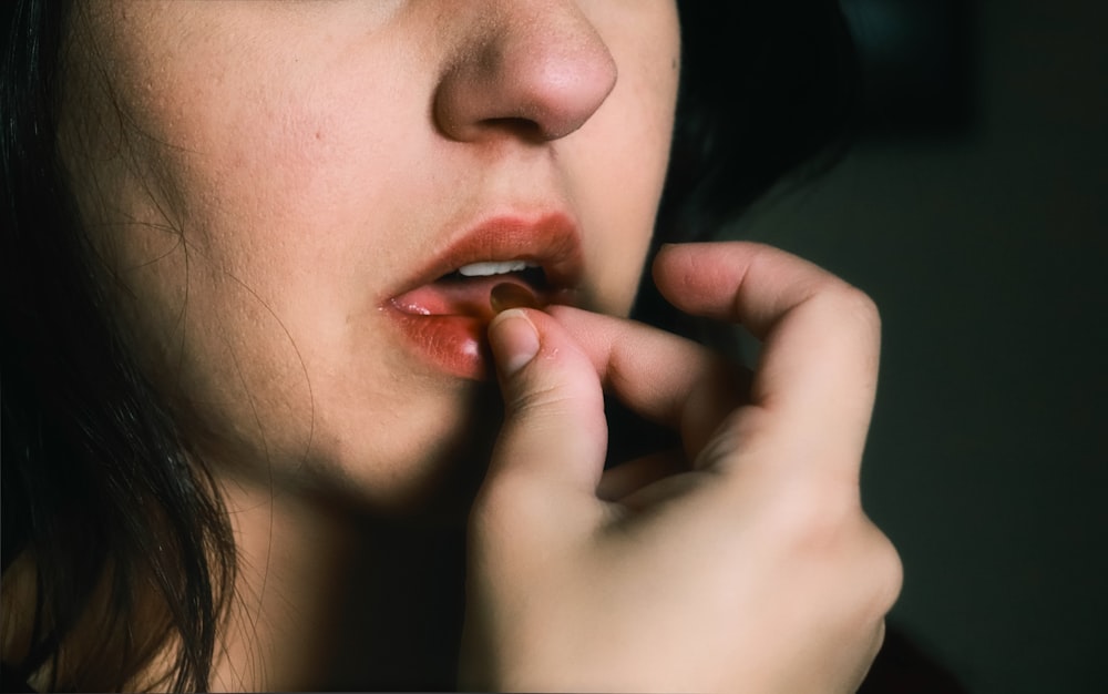 mujer con lápiz labial rojo sosteniendo sus labios