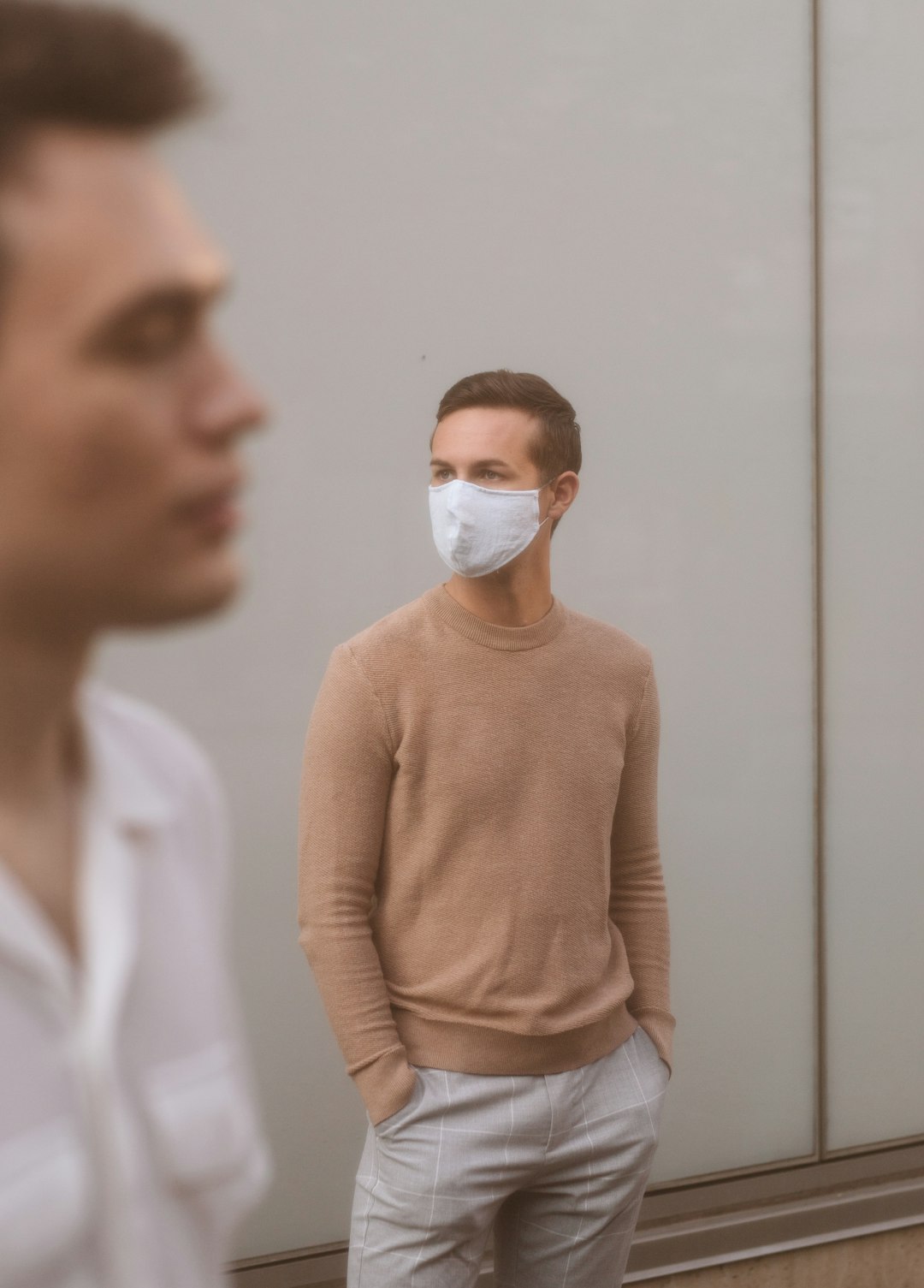 woman in brown sweater wearing white face mask