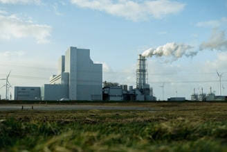 white and gray factory under white clouds during daytime