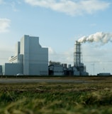 white and gray factory under white clouds during daytime