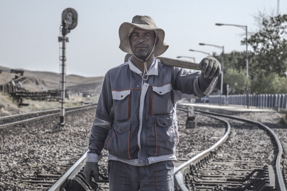 homme en veste zippée noire et rouge debout sur le rail de train pendant la journée