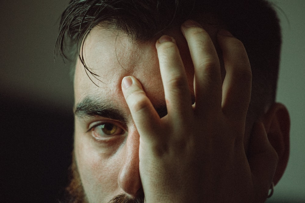 man covering his face with his hand