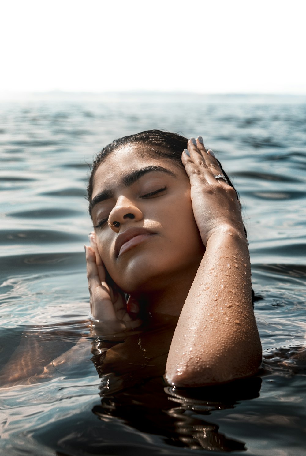 woman in water covering her face with her hands