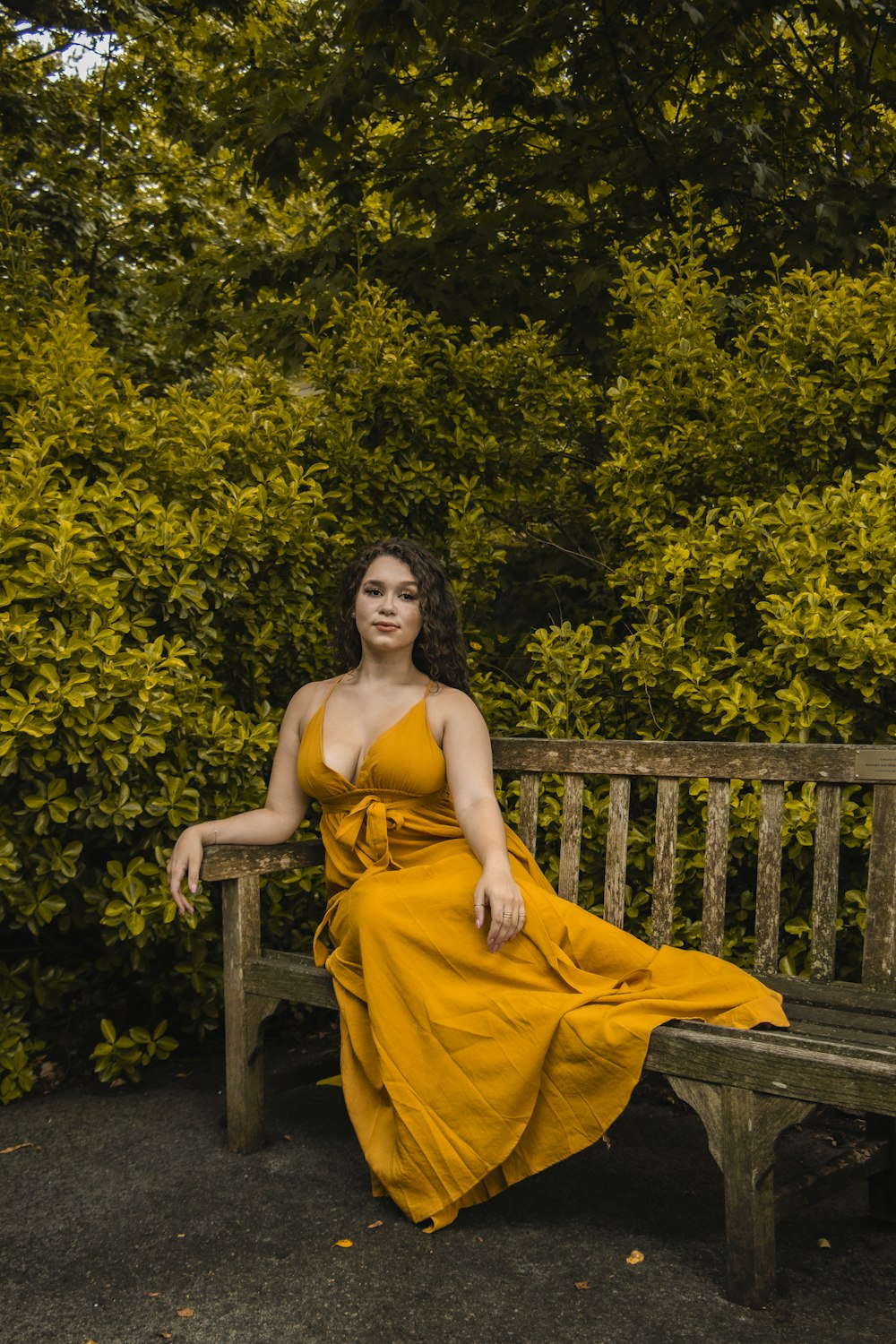 woman in yellow spaghetti strap dress sitting on brown wooden bench