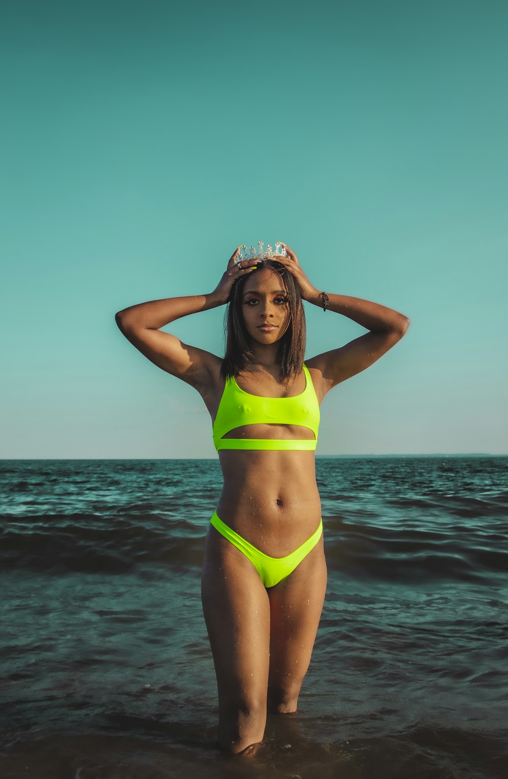 woman in green bikini top and white hat standing on beach during daytime