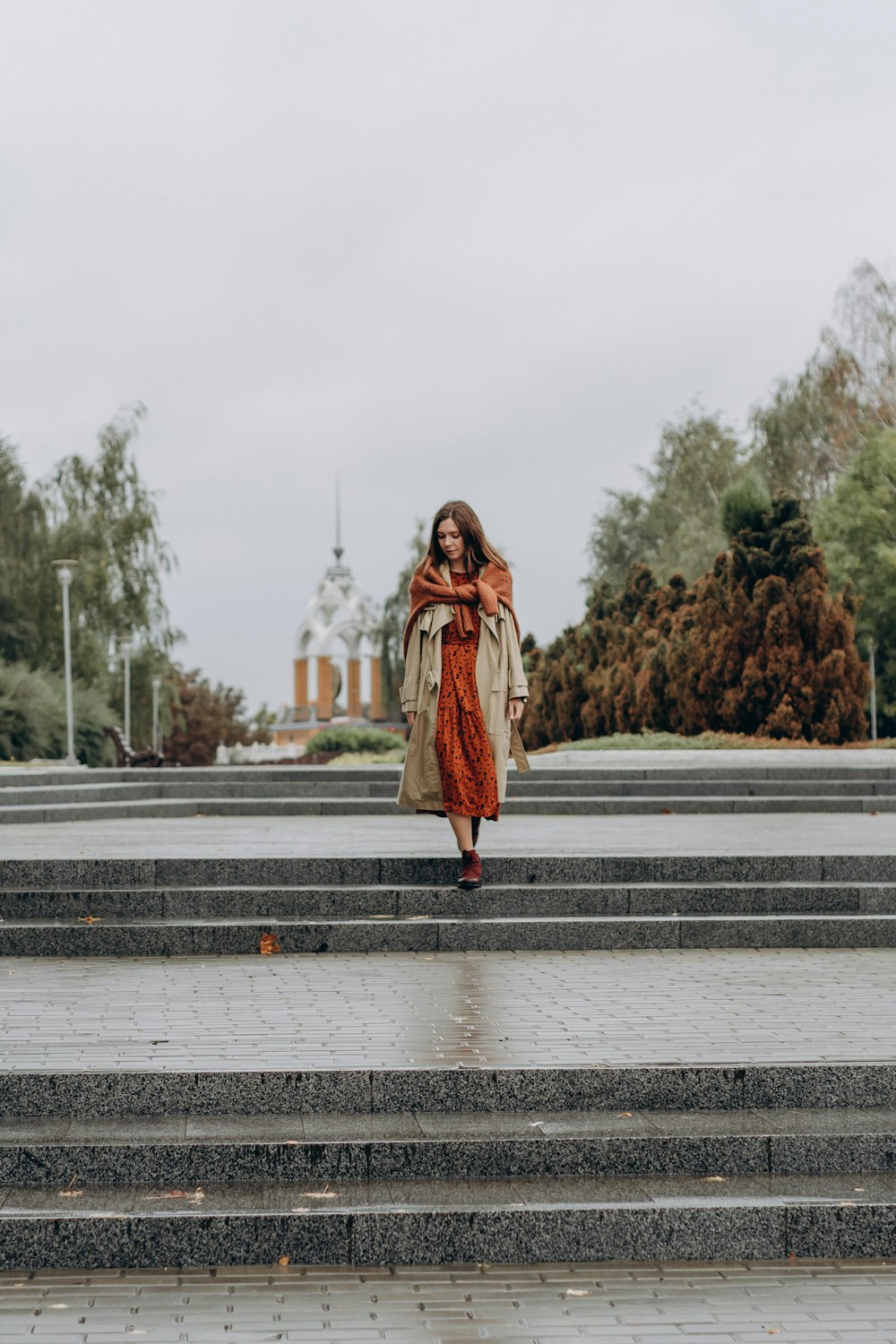 woman in brown coat standing on gray concrete road during daytime