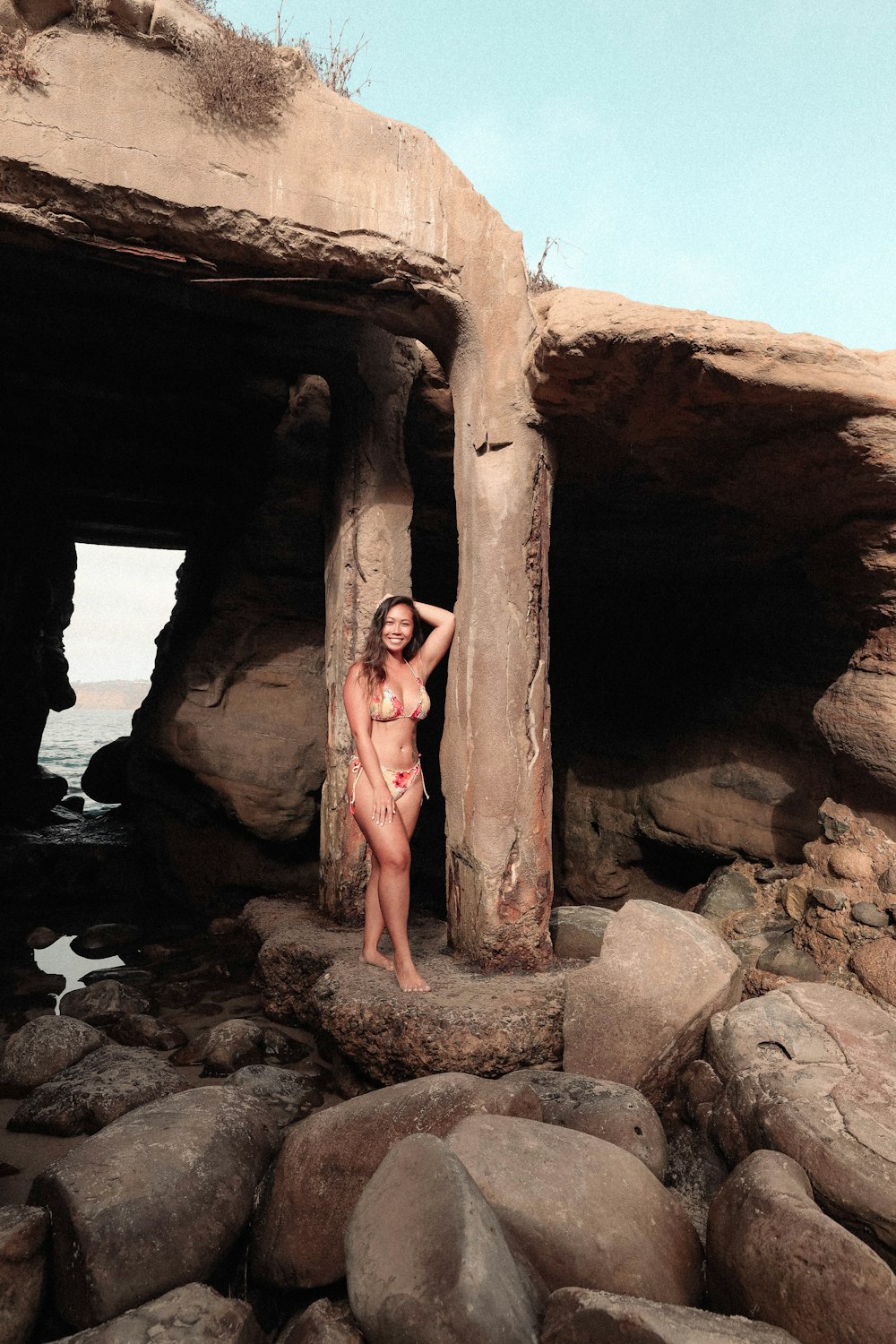 a woman in a bikini standing next to a rock formation