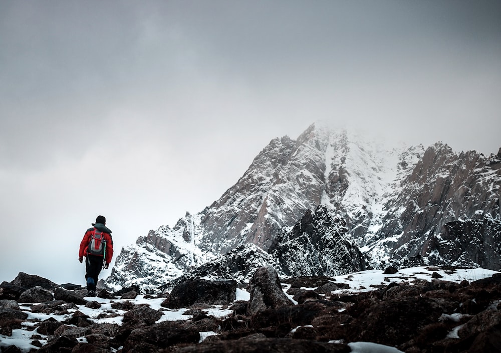 man in red jacket standing on rocky mountain during daytime