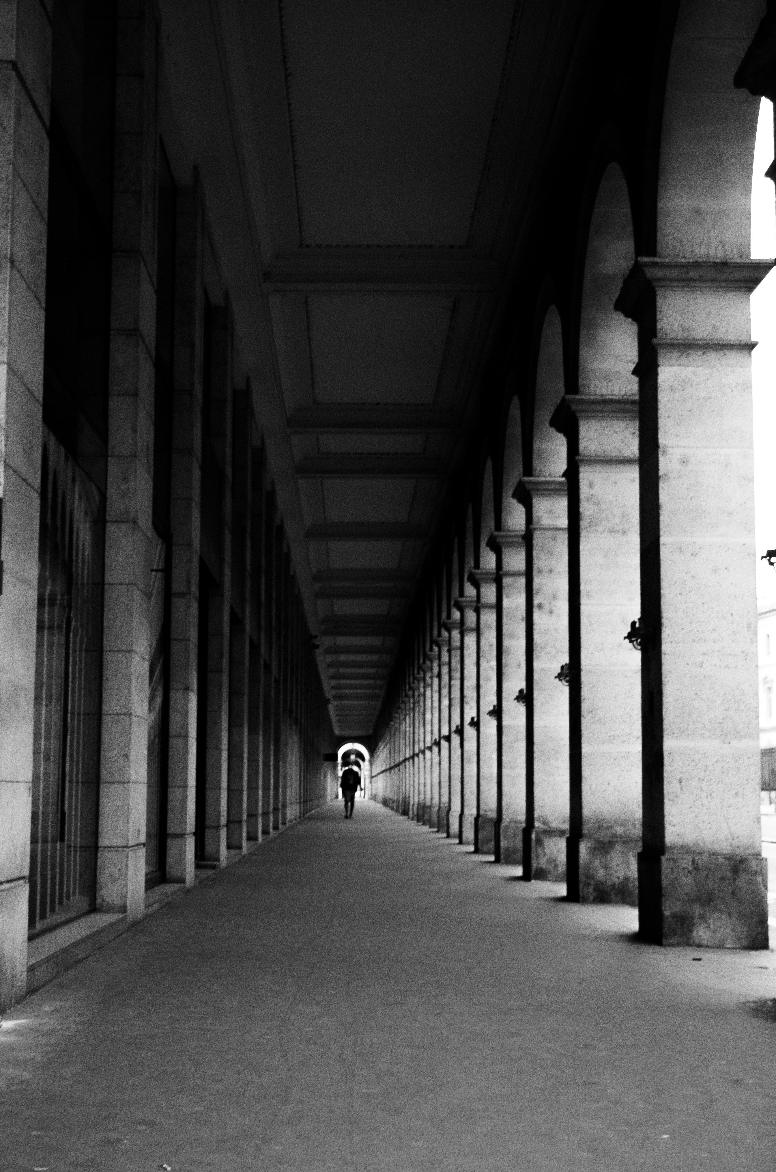 grayscale photo of person walking on hallway