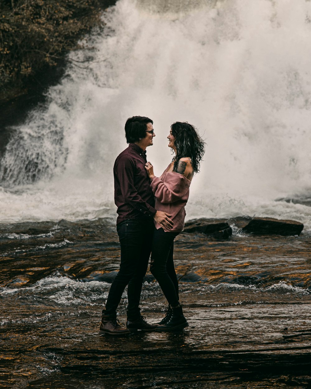 man in brown jacket and black pants standing on water falls