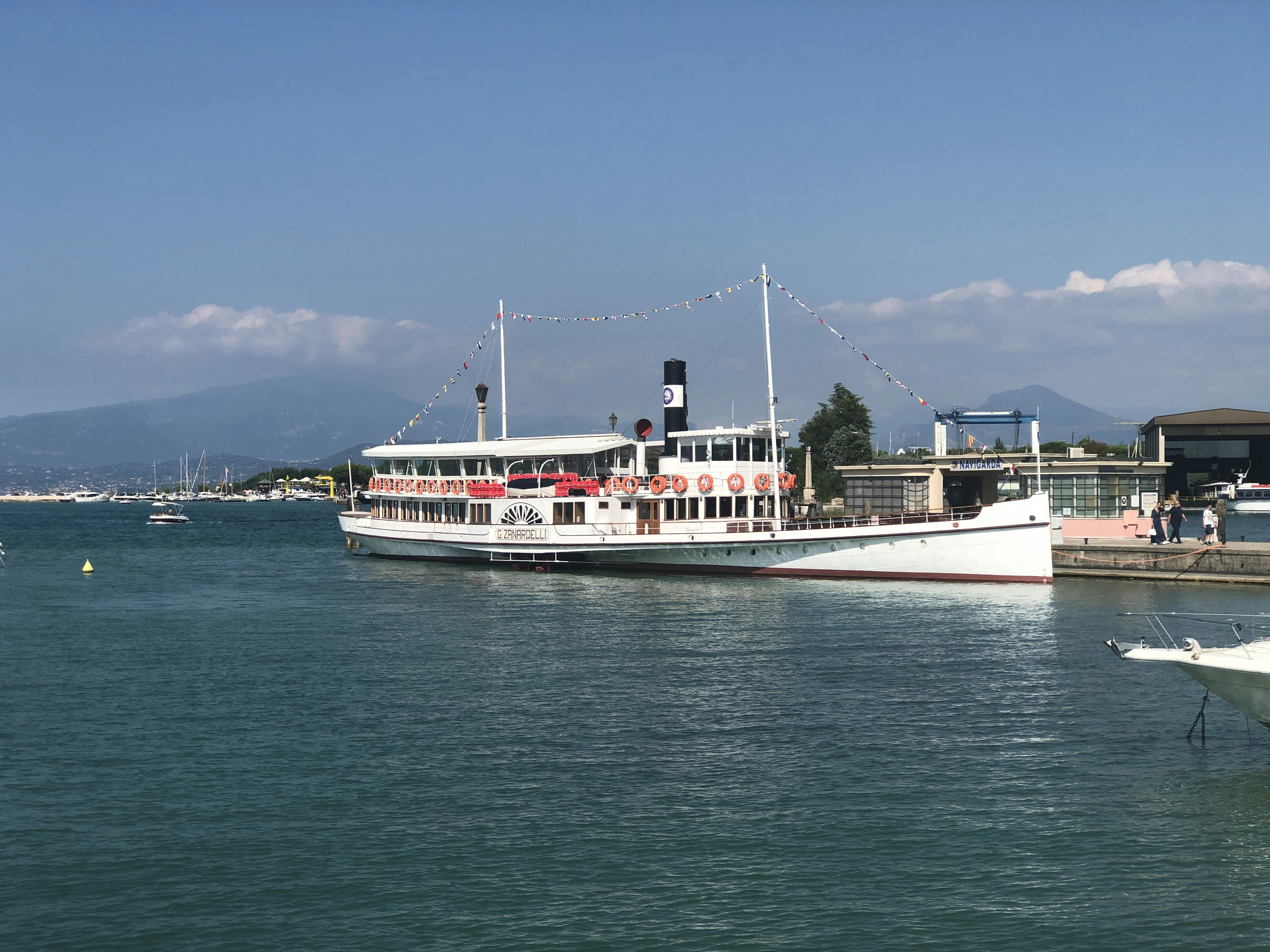 昼間の青空の下、海に浮かぶ白と赤の船
