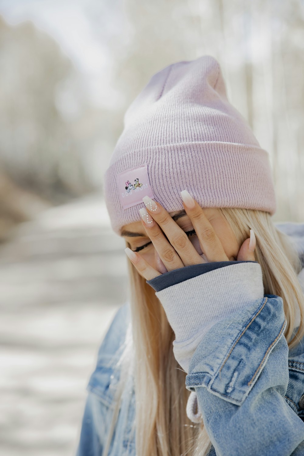 woman in pink knit cap covering her face with her hand