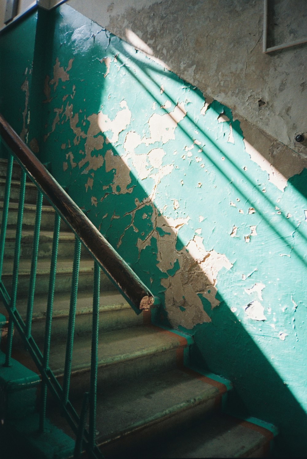 teal metal railings near green concrete wall