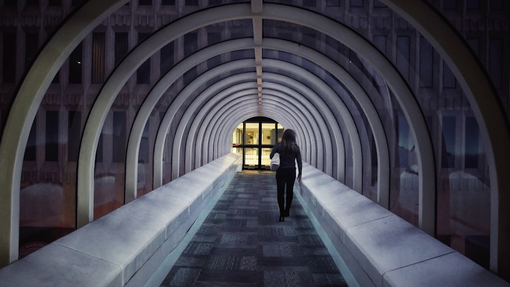 man in black jacket walking on tunnel