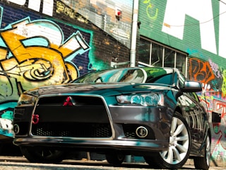 A sleek black car parked in front of a vibrant São Paulo street mural.
