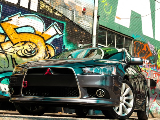 A sleek car partially wrapped in a vibrant vinyl design parked in an urban setting.