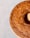 A golden-brown bundt cake with a textured surface is placed on a light speckled background. The cake has a smooth, uniform color and appears freshly baked, with a shine indicating a moist crumb.