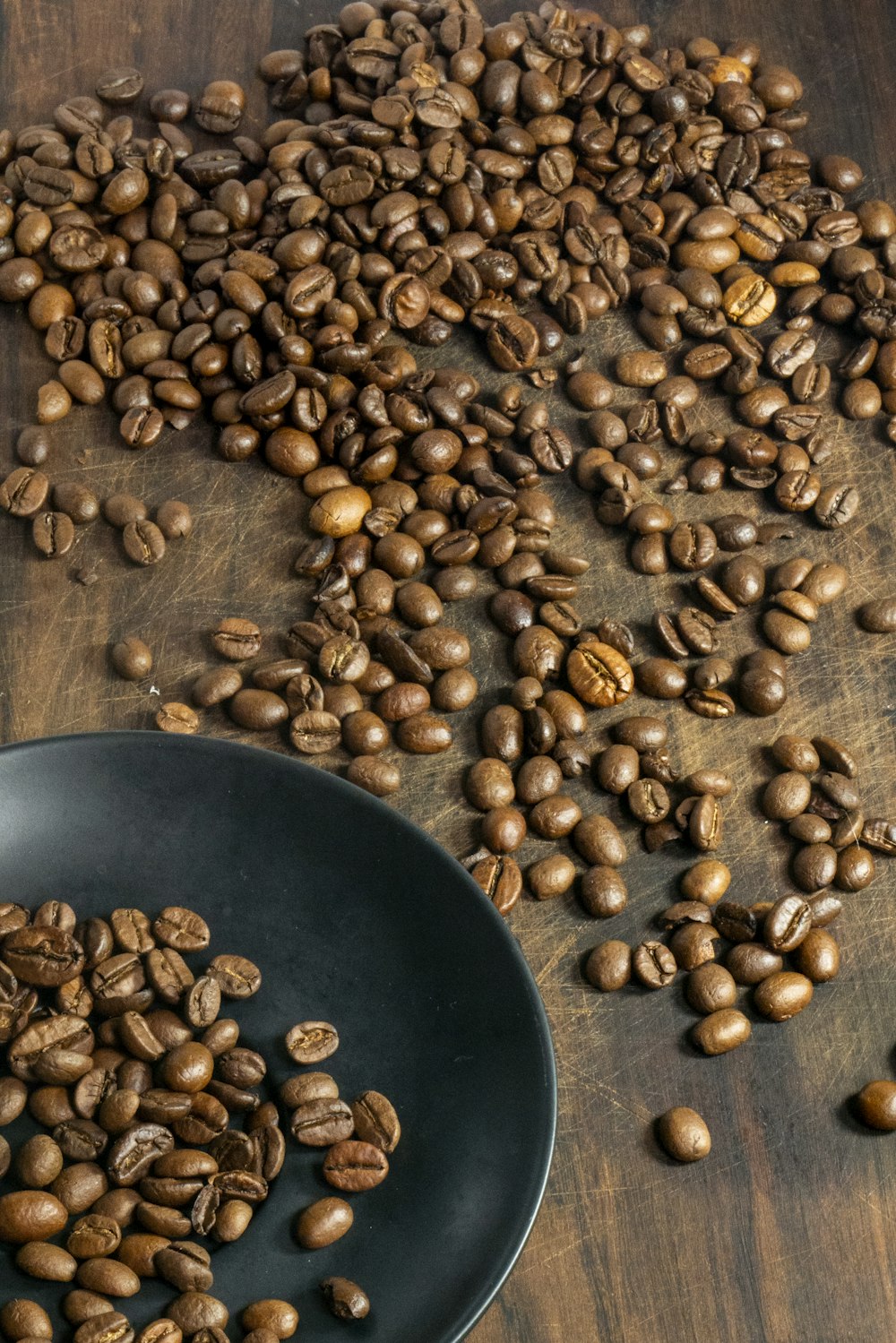 braune Kaffeebohnen auf schwarzem runden Teller