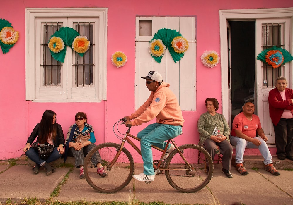 man in pink dress shirt riding on bicycle