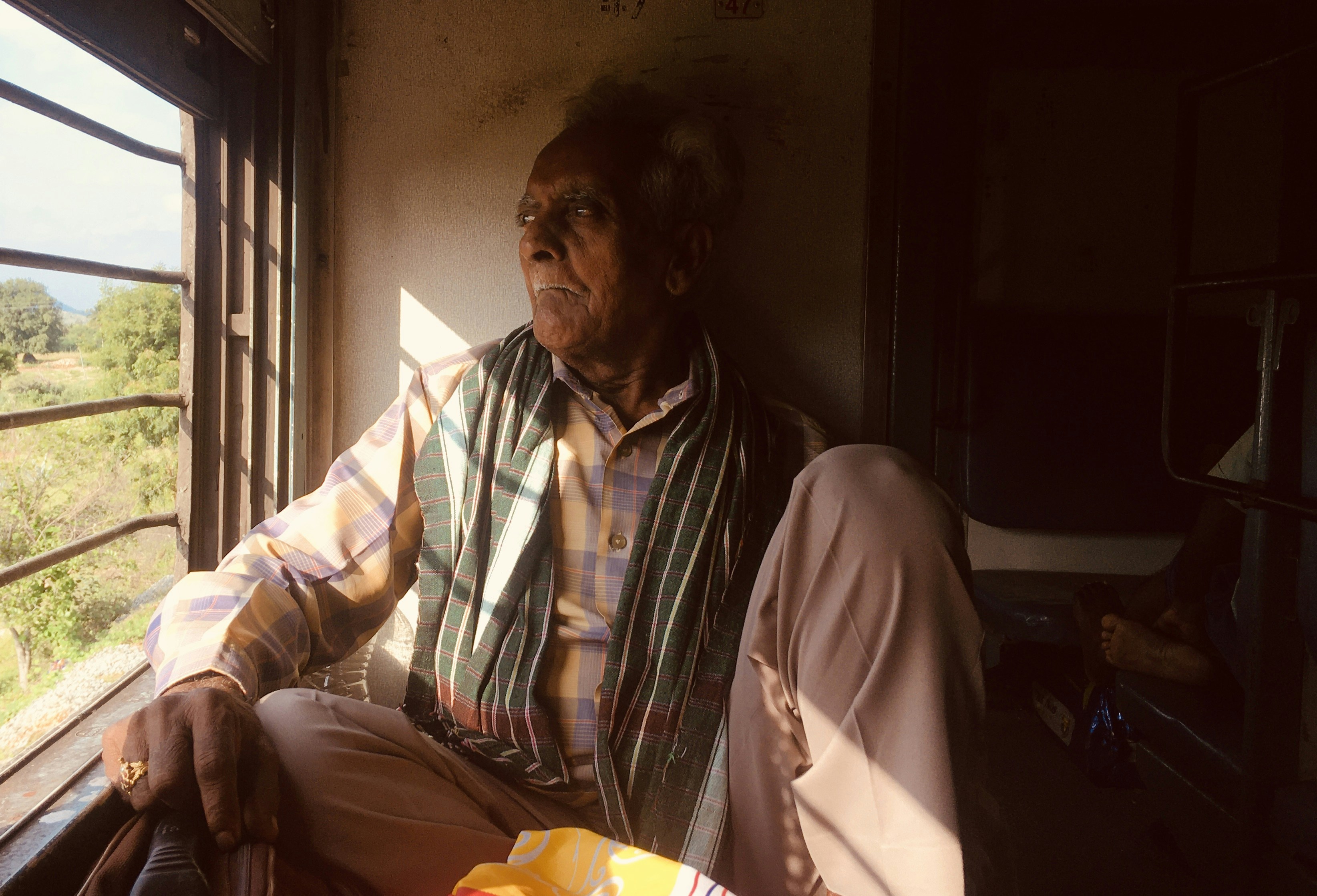 Mann in weiß-rot kariertem Hemd sitzt auf braunem Ledersessel